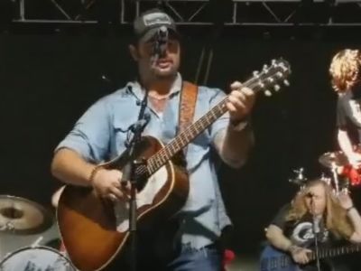 Koe Wetzel is singing while playing his guitar.